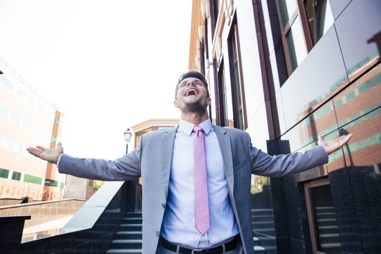 Handsome excited businessman celebrating his success outdoors